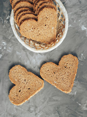 Rye bread in the shape of heart cut into slices on a gray background