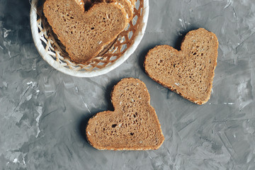 Rye bread in the shape of heart cut into slices on a gray background