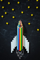  Rocket Made From Colored Pencils And Chalk On Black Chalkboard Background Shooting For The Stars - Back To School / Business Entrepreneur Concept