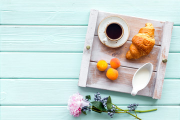 croissant, fruit and coffee with cream for homemade breakfast on the tray mint green wooden background top view mockup