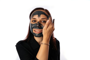 A young woman inflicts a black mask on the face isolated on white background.The concept of healthy lifestyle, beauty, body care.