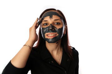 A young woman inflicts a black mask on the face isolated on white background.The concept of healthy lifestyle, beauty, body care.