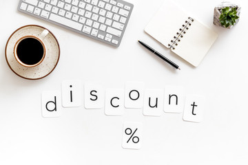 Discounts concept with discount text and percent sign, notebook, keyboard, coffee on white background top view