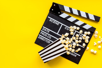Fototapeta na wymiar Movie premiere concept with clapperboard, popcorn on yellow background top view space for text