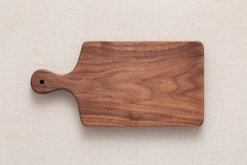 Walnut handmade wood cutting board on the linen	