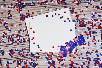 Three red, white and blue Australian flags suspended from a twine rope in front of a grungy, steel background for Australia Day on January 26. Thematic message across bottom of horizontal image.