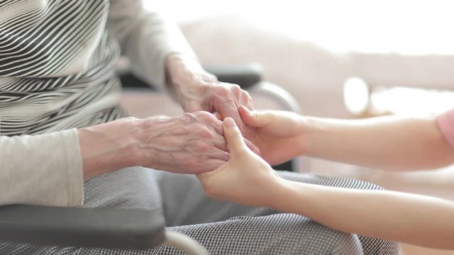 Caregiver holding hand of senior woman in nursing home