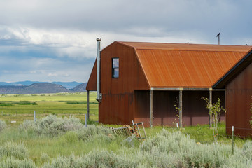 Red farm shed in a big grassland farm field with the mountain on the background.  Eastern Sierra Mountains, Mono County, California, USA
