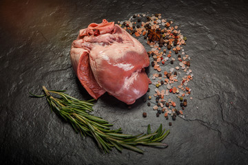 top view on big beef raw heart with spices and rosemary