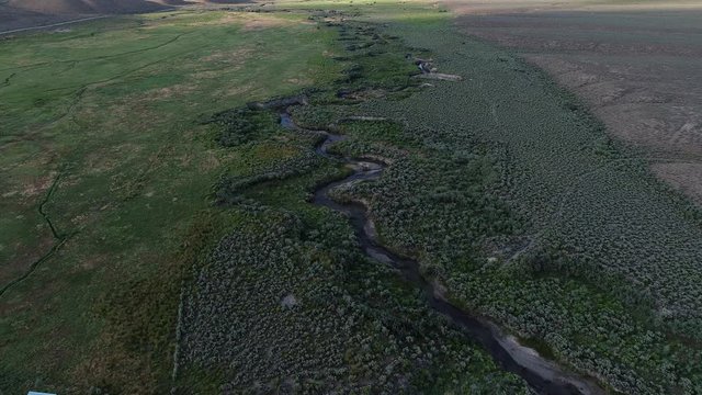 Flying over a twisty river in a lush desert valley.