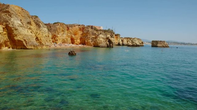 Wide angle shot of Pinhao Beach, Lagos, The Algarve, Portugal, a secluded cove with clear water and towering orange cliffs