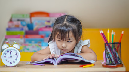 Little student girl  reading a book or doing homework at home .The decision of lessons. education and school concept.