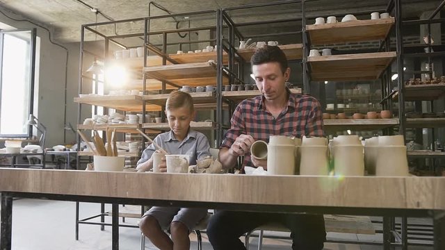 Caucasian cute father with little son making pattern on the vase.