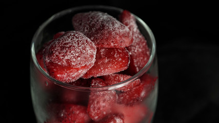 Frosty strawberries in glass on black background