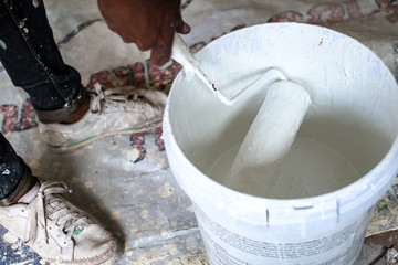 Paint roller inside the paint bucket with white color liquid at construction site for a new building house.