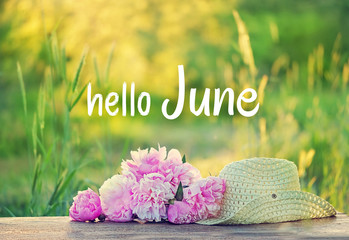 Hello June. beautiful pink peonies and summer hat outdoors.Rural landscape natural background with pink flowers and braided hat in sunlight garden. Summer time season. soft selective focus