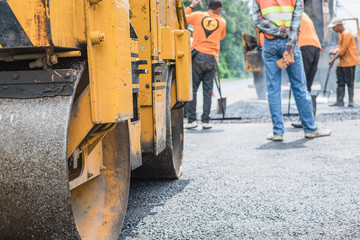Small asphalt roller in on duty repairing repairing asphalt road. Workers on a road construction,...