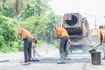 Group of workers working on repairing asphalt road. Workers on a road construction, industry and teamwork.