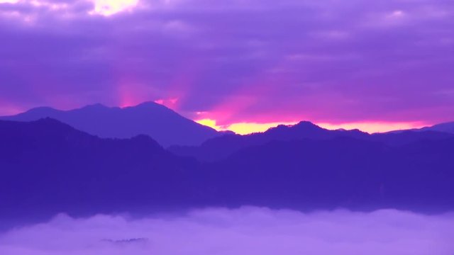 Timelapse of clouds flowing over mountains at sunrise