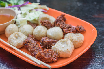 Thai fried meat balls served with spicy dipping chili sauce and vegetable. Popular appetizers side dish roasted meat balls. Thai street food.