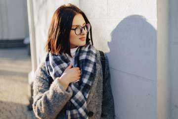 Attractive young girl wearing glasses in a coat walking on a sunny day
