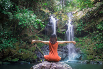 Female doing yoga outdoor exercise for Health is relaxation at beautiful waterfall.