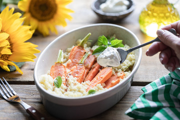 Young carrots baked with Pravanese herbs. couscous Sour cream, yogurt or fresh cream. Flowers sunflower wooden table