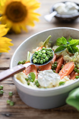 Young carrots baked with Pravanese herbs. couscous Sour cream, yogurt or fresh cream, young green peas. Flowers sunflower wooden table