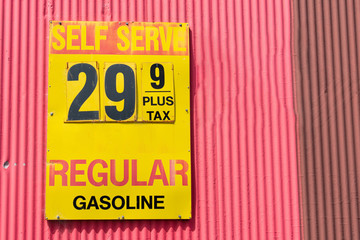 Vintage gas station price sign advertising pre-inflation gasoline prices on the red barn wall