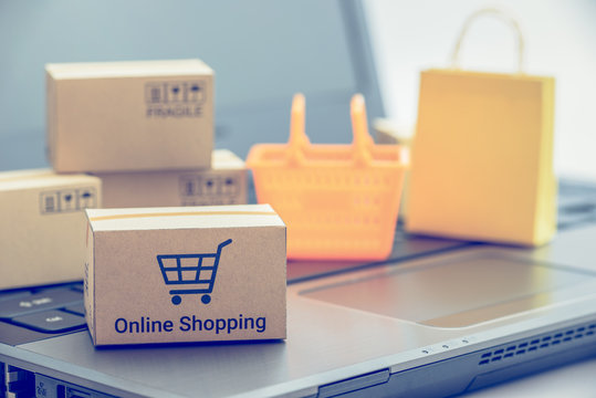 Shop online, ecommerce / retail commerce concept : Box or cartons with trolley or shopping cart, shopping basket on a laptop computer, depicts new lifestyle customers buy products via online store.