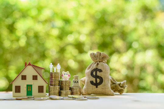 Money saving, first time asset buyer concept : Family couple, home model, piggy bank, dollar and tax bags, stacks of rising coins
