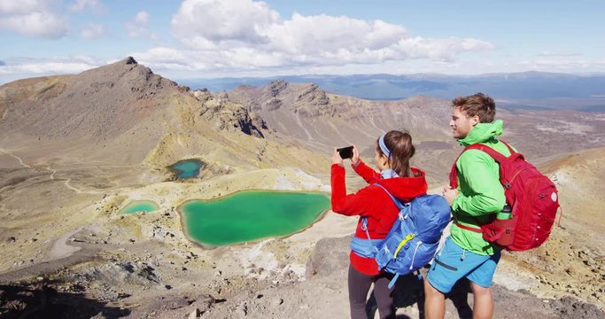 New Zealand Travellers photographing volcanic landscape by Emerald Lakes. Man and woman hikers in Tongariro National Park. Couple enjoying vacation in New Zealand on North Island. SLOW MOTION.