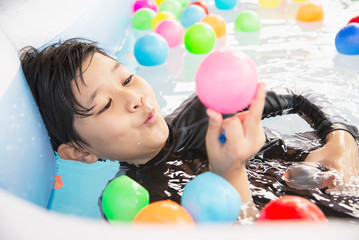 Fototapeta na wymiar Boy playing with colourful ball in small swimming pool toy - happy boy in water pool toy concept