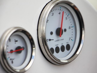 Main analog devices on the white dashboard control panel of the motor boat close-up: tachometer with 4200 rpm and trim meter