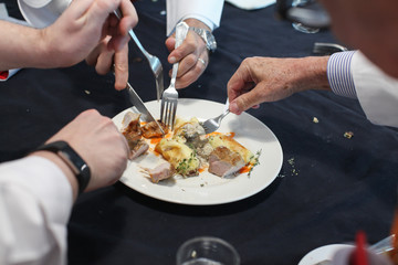 The blurred background of the group of foodies is dividing the food in the dish to taste.