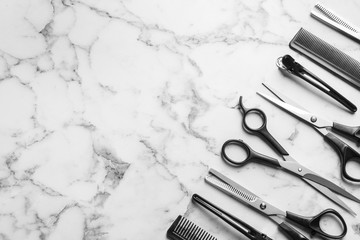 Flat lay composition with scissors and other hairdresser's accessories on white marble background....