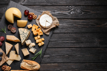 Different types of delicious cheese served on black wooden table, top view. Space for text