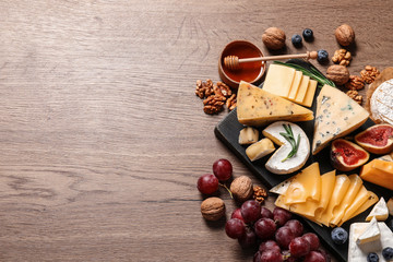 Different types of delicious cheese served on wooden table, top view. Space for text