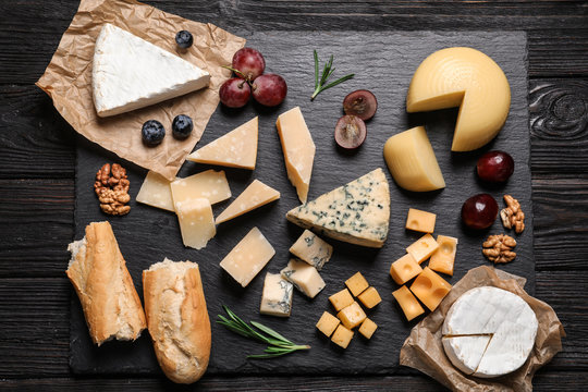 Flat lay composition with different types of delicious cheese on slate board