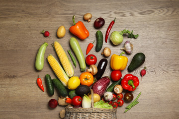 Flat lay composition with different vegetables and wicker basket on wooden background