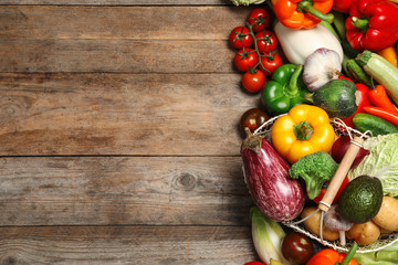 Fresh vegetables and metal basket on wooden table, flat lay. Space for text