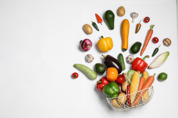 Fresh vegetables and metal basket on white background, top view