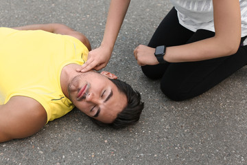 Obraz premium Young woman checking pulse of unconscious man on street