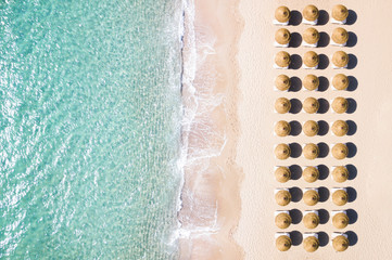View from above, stunning aerial view of an amazing white beach with beach umbrellas arranged symmetrically and a beautiful turquoise clear water. Sardinia, Italy.