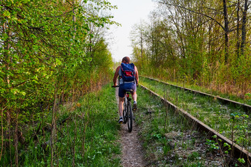 Obraz premium Landscape with railway, trees, grass and cyclist. Nature in spring or summer evening