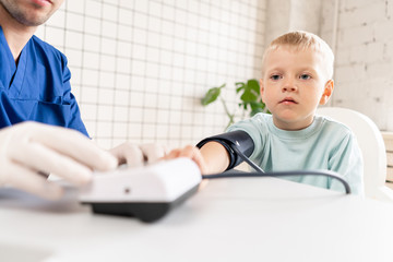 Little boy visiting doctor in hospital. Measuring blood pressure and checking pulse