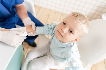 Fototapeta premium Doctor bandaged a boy hand with trauma in his arm. Elastic bandaged around his hand