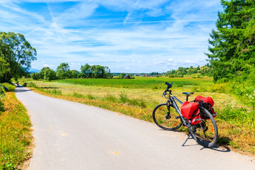 NOWY TARG, POLAND - JUN 29, 2019: Touring bike on cycling way in green farming fields along Dunajec river, Pieniny Mountains, Poland.