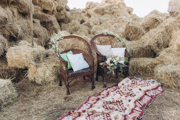 Wedding asymmetrical stylish bouquet with roses on a boho wicker chair.
