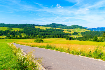 Cycling road around Tatra Mountains and green fields on summer day with beautiful blue sky, Poland